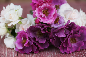 Fototapeta na wymiar Bouquet of pink and purple garden roses on a wooden background