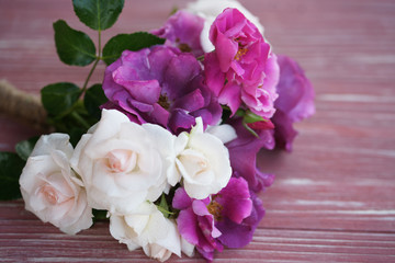 Bouquet of pink and purple garden roses on a wooden background