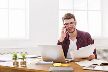 Young concentrated businessman read documents in modern white office