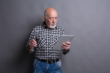 Senior man reading news on digital tablet