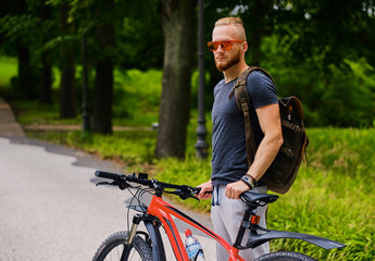 A man sits on a red mountain bicycle outdoor.