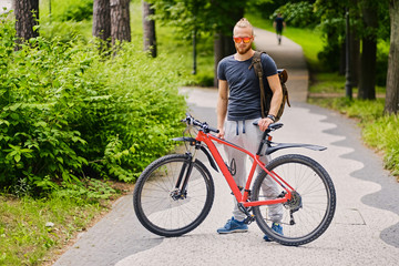 Fototapeta premium A man sits on a red mountain bicycle outdoor.