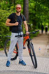A man sits on a red mountain bicycle outdoor.