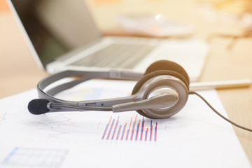 close up earphone of call center lay on paperwork with laptop computer on desktop