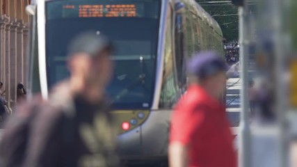 Pedestrians crossing street, public transport carrying passengers, city traffic