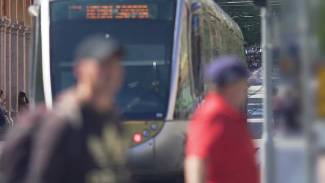 Pedestrians crossing street, public transport carrying passengers, city traffic