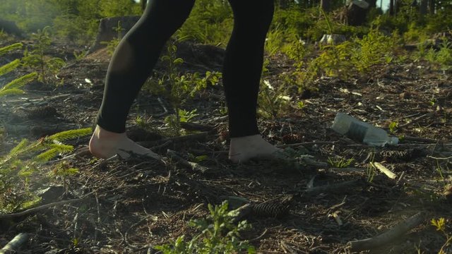 Woman slowly walking barefeet through the harvested spruce forest