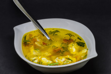 A delicious soup with vegetables and fish on a black background, very healthy healthy food in a white bowl.