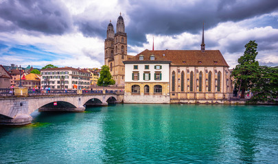 Fototapeta premium Zurich with famous Fraumunster Church and Munsterbucke crossing river Limmat on a sunny day with blue sky and clouds in summer, Canton of Zurich, Switzerland