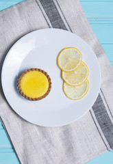 Lemon cake on a white plate with slices of lemon, taken on a blue background
