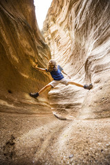 boy with long hair hikes up a slot canyon in the southwest 