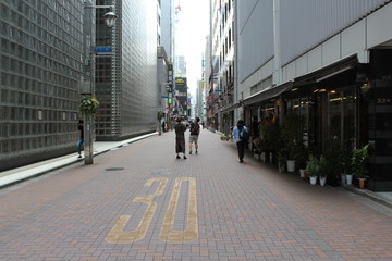 People walking on the street in tokyo near to maison hermes by renzo piano architecture