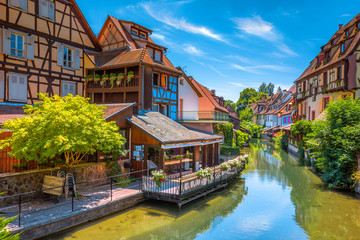 Beautiful view of the historic town of Colmar, also known as Little Venice, with tourists taking a boat ride along traditional colorful houses on idyllic river Lauch in summer, Colmar, Alsace, France - obrazy, fototapety, plakaty