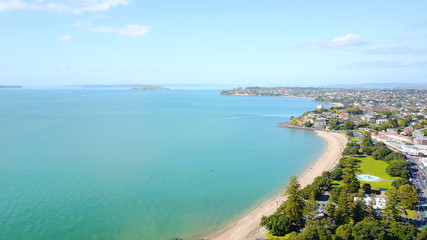 Aerial view on sunny beach with residential suburb on the background. Auckland, New Zealand.