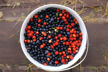 Blueberries and strawberries on an old wooden table in the bucket