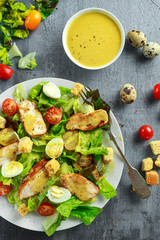 Fresh healthy Caesar salad with chicken, egg quail, tomatoes, Cheese and Croutons in a white plate
