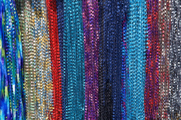 Background fabric strings creating scarfs, multiple colored scarves hanging in rows. yellow, red, blue, purple, maroon, aqua