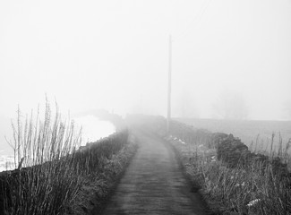 fog on a country lane vanishing into the distance with with snow and stone walls