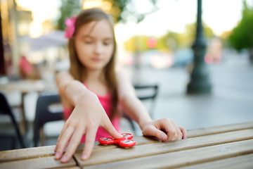 Cute school girl playing with colorful fidget spinner