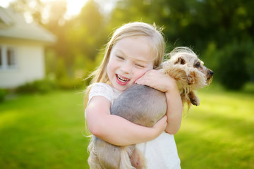 Cute little girl holding her funny yorkshire terrier dog