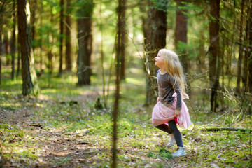 Adorable little girl picking the first flowers of spring in the woods on beautiful sunny spring day.