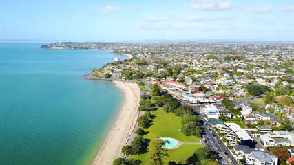 Aerial view on sunny beach with residential suburb on the background. Auckland, New Zealand.