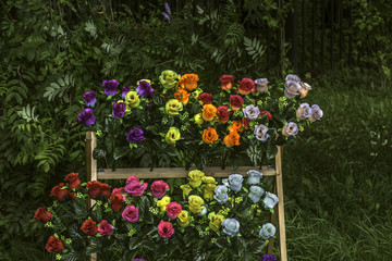 Fototapeta na wymiar Artificial flowers for sale near cemetery fence