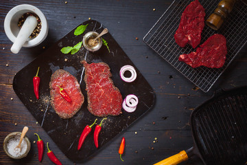 Raw ribeye beef steak on black marble deck on an old rustic table. Top view