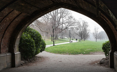 Fototapeta na wymiar View through the arch in foggy day in the Brooklyn park, New York landscape.
