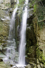 Fototapeta na wymiar Large rain forest waterfall, sun beams, and mossy rocks