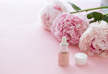 Cosmetics bottles on the pink background with flowers.Close up