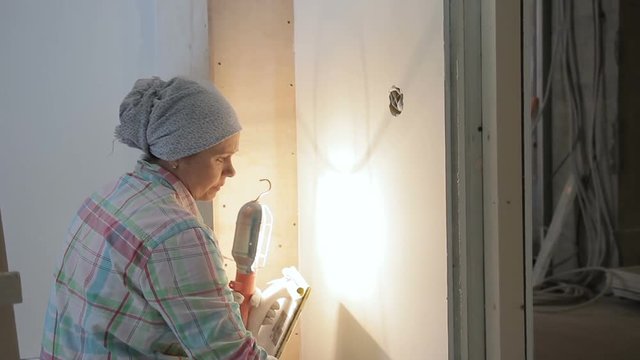 Repairman carefully polishing the wall and illuminates the lamp