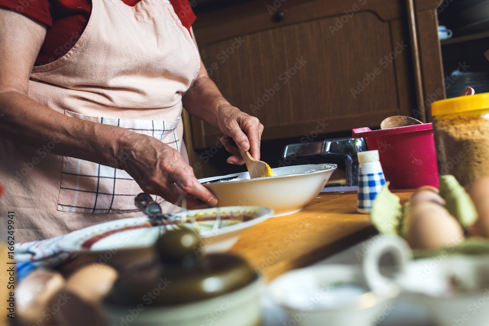 Wall mural Close up of female baker hands kneading dough.