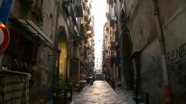 View of narrow passage between high walls of houses in Naples street, Italy