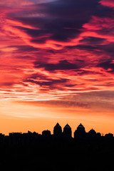 colorful fiery sky with altocumulus clouds at sundown above the city skyline 