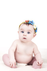 portrait of cute baby girl with blue and yellow flowers headband on her head, on white background