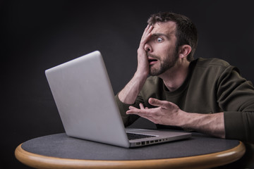 Young man shocked and surprised with the content he sees on his laptop