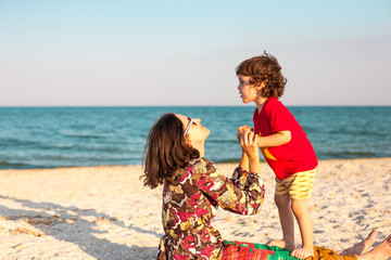 Mother plays with her baby on the beach.