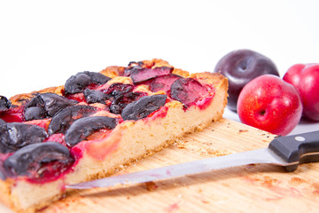 Plum pie on a wooden chopping board on a white background