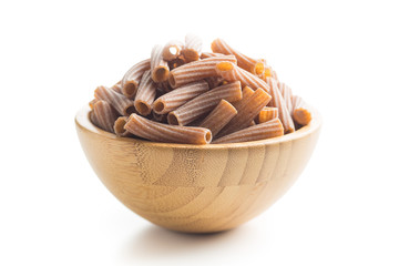 Dried rigatoni pasta in wooden bowl.