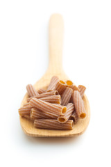 Dried rigatoni pasta on wooden spoon.