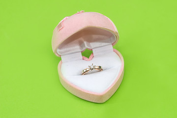 Marriage. Gold ring in pink present box in green background