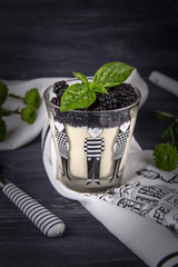 Homemade italian dessert panna cotta with fresh blackberries and green basil on a dark background