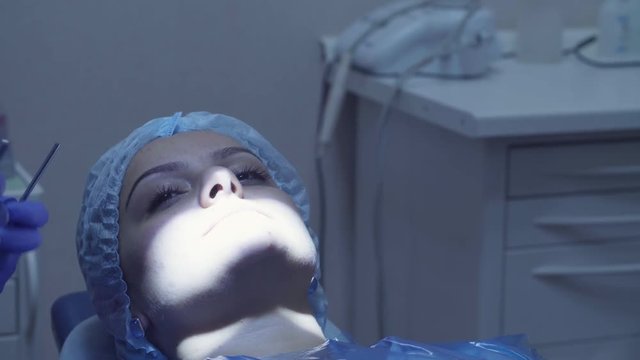 Dentist cheking woman's teeth with mirror