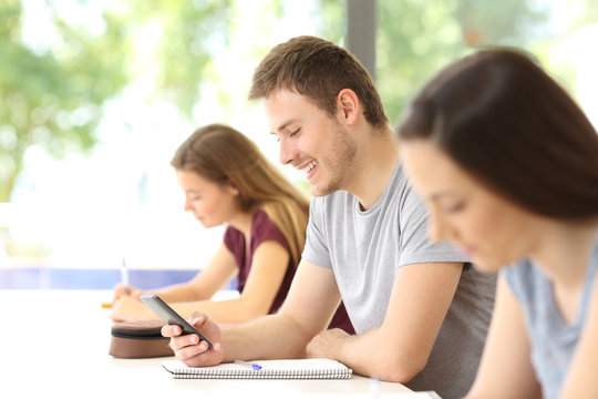 Student distracted with mobile phone at classroom
