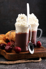 Iced coffee with whipped cream in tall glass and fresh croissant