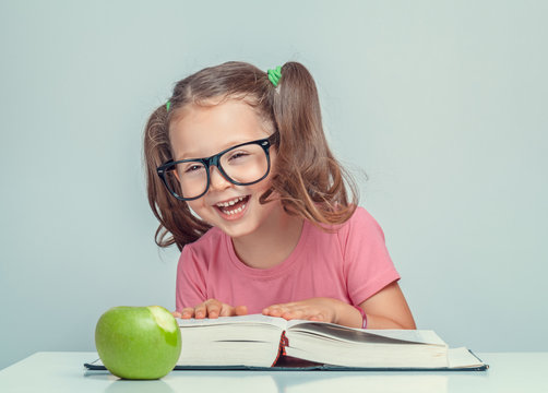 beautiful cute little girl with book and green apple having fun