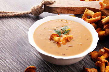 Mushroom cream soup with fresh chanterelles and herbs on a rustic background. Autumn concept.