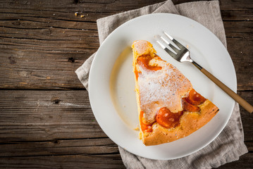 Homemade autumn and summer baked pastries. Sponge cake with apricots. Cut into pieces, plate, fork. On the old wooden rustic table. Copy space top view