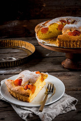 Homemade autumn and summer baked pastries. Sponge cake with apricots. Cut into pieces, plate, fork. On the stand. On the old wooden rustic table. Copy space